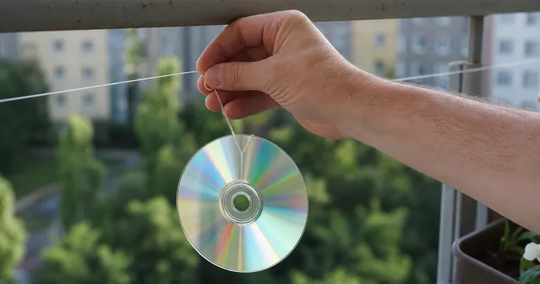 Dłoń zawieszająca błyszczącą płytę na sznurku przy balustradzie